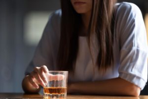 a person taps a drink while pondering the difference between casual drinkers and alcohol abusers
